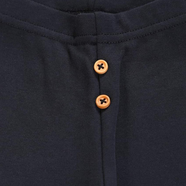 Close-up of navy kids thermal wear fabric with two brown buttons on the front placket.