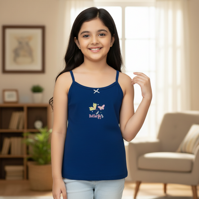Smiling girl wearing blue sleeveless camisole top with butterfly print, indoors.