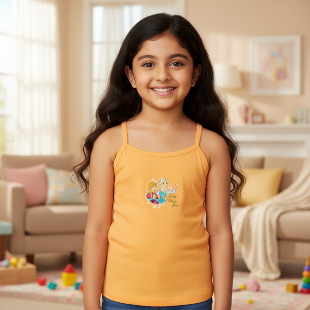 Smiling girl in yellow camisole with cartoon print, standing in cozy living room setting.