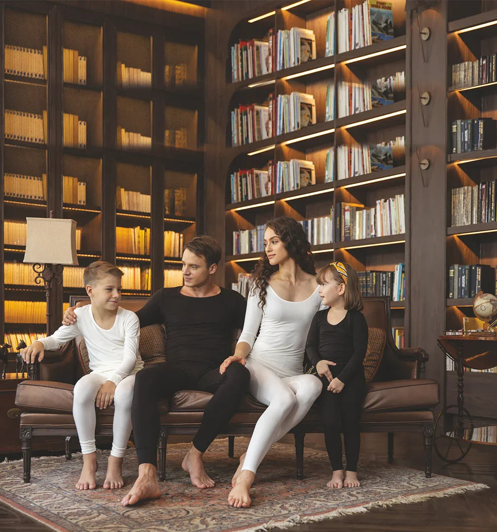 Family wearing kids and adults thermal innerwear sitting on sofa in cozy library