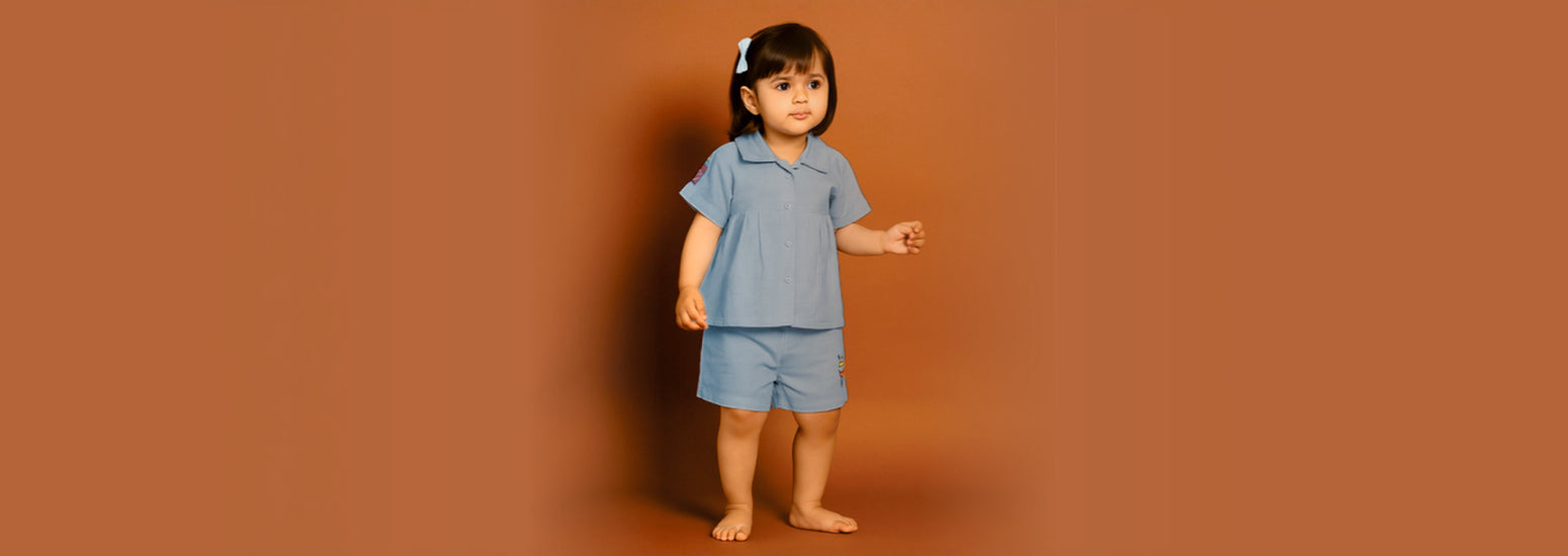 Young girl in blue kids nightwear set standing against a plain brown background