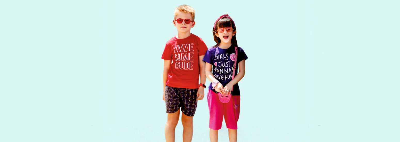Two kids in colorful summer apparel, graphic t-shirts and shorts, smiling outdoors