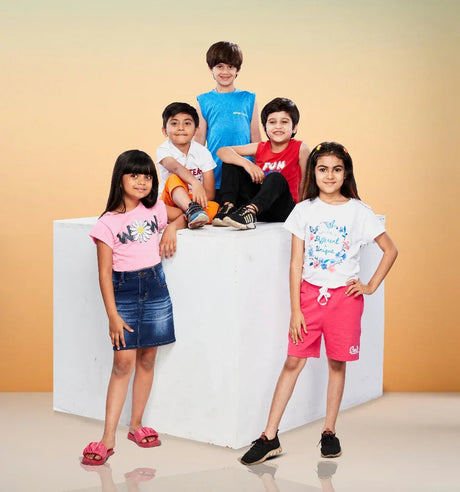 Group of kids in colorful summer apparel posing cheerfully against a soft orange background