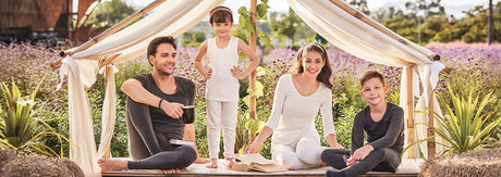 Family in soft thermal innerwear sitting outdoors under a fabric tent in a garden