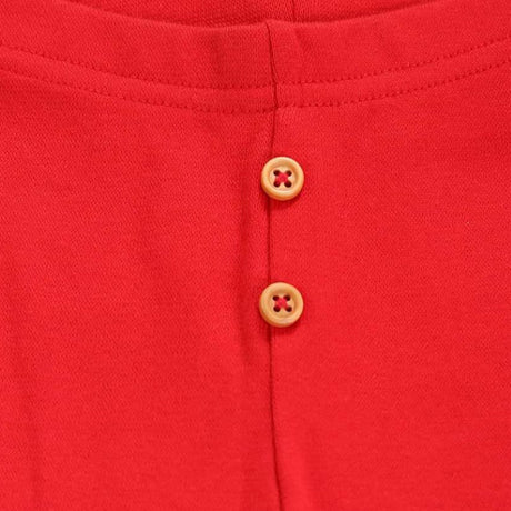 Close-up of red kids innerwear fabric with two tan buttons, soft cotton material