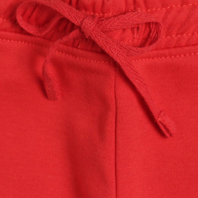 Close-up of red kids pants with elastic waistband and drawstring tie, soft fabric