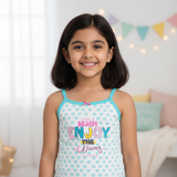 Smiling girl in blue star print kids camisole with 'Enjoy the Waves' text, indoor setting